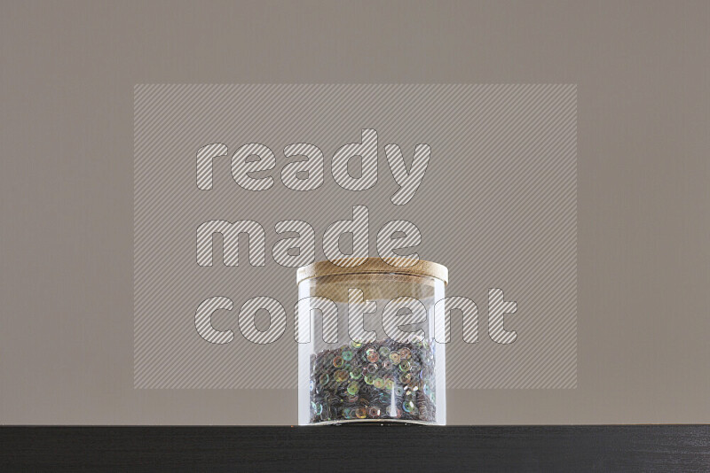 Sequins in a glass jar on black background