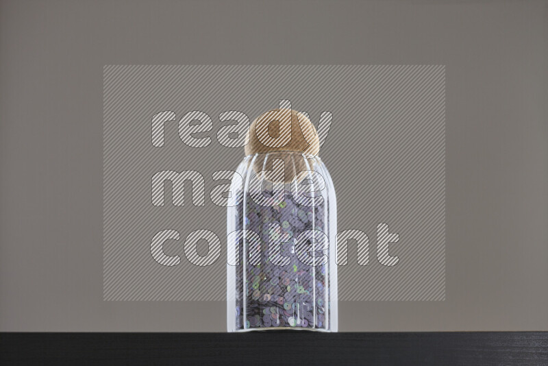 Sequins in a glass jar on black background