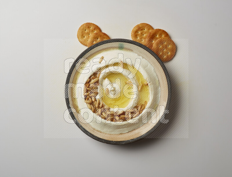 Lebnah garnished with pine nuts in a pottery plate on a white background