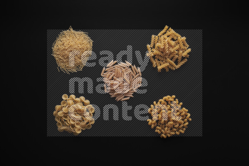 Different pasta types in bunches on black background