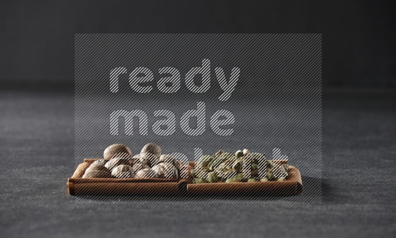 2 squares of cinnamon sticks full of nutmegs and cardamom on black flooring