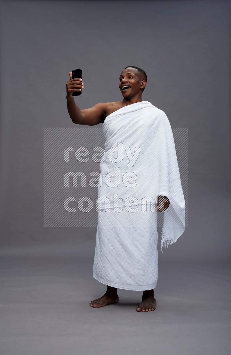 A man wearing Ehram Standing taking selfie on gray background