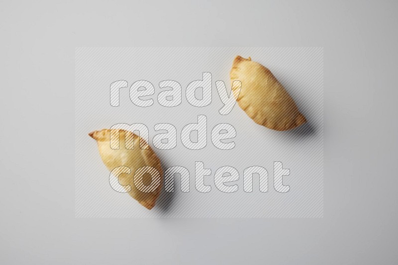 Two fried sambosa from a top angle on a white background