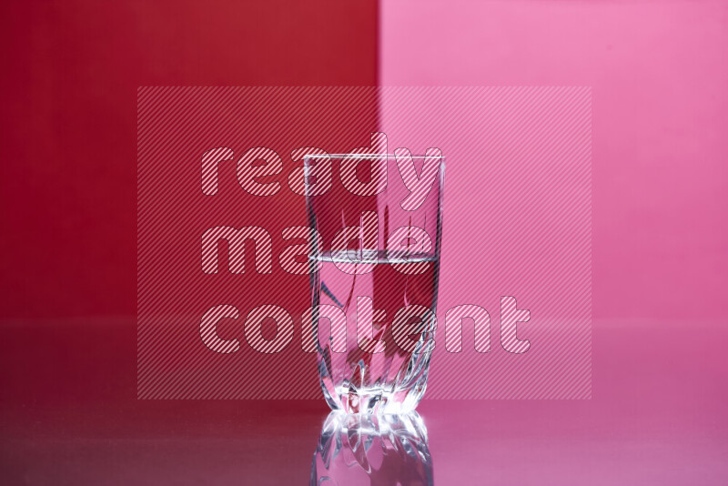 The image features a clear glassware filled with water, set against red and pink background