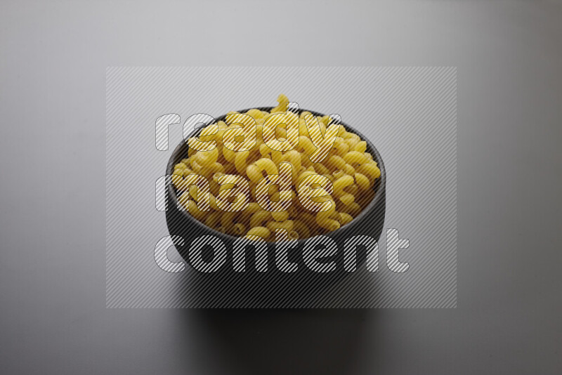Twist pasta in a pottery bowl on grey background