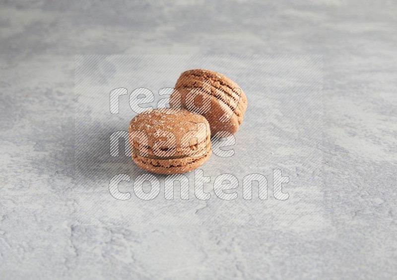 45º Shot of two Brown Hazelnuts macarons  on white  marble background