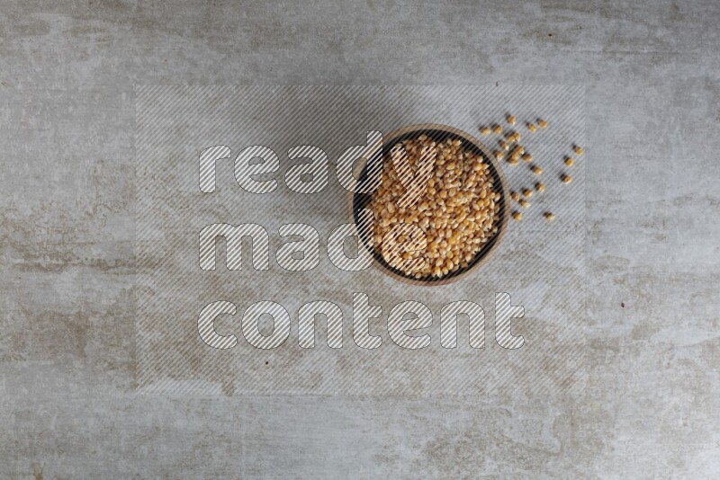 corn kernel in a wooden bowl on a grey textured countertop