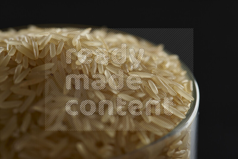 Basmati golden rice in a glass jar on black background