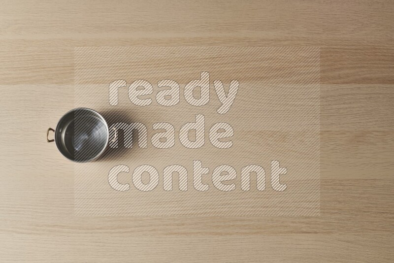 وعاء نحاسي صغير على خلفية خشبية فاتحة