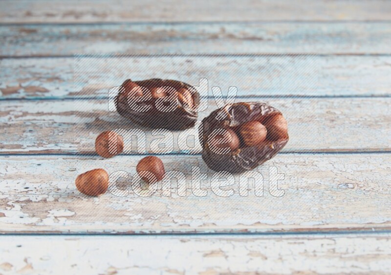two hazelnuts stuffed madjoul dates on a light blue wooden background