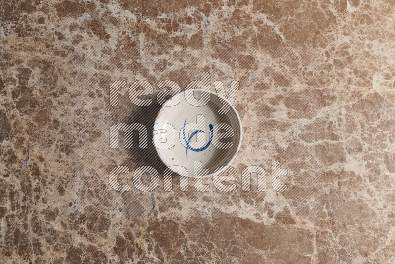 A multicolored pottery bowl on beige marble background