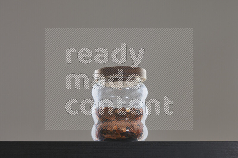 Sequins in a glass jar on black background