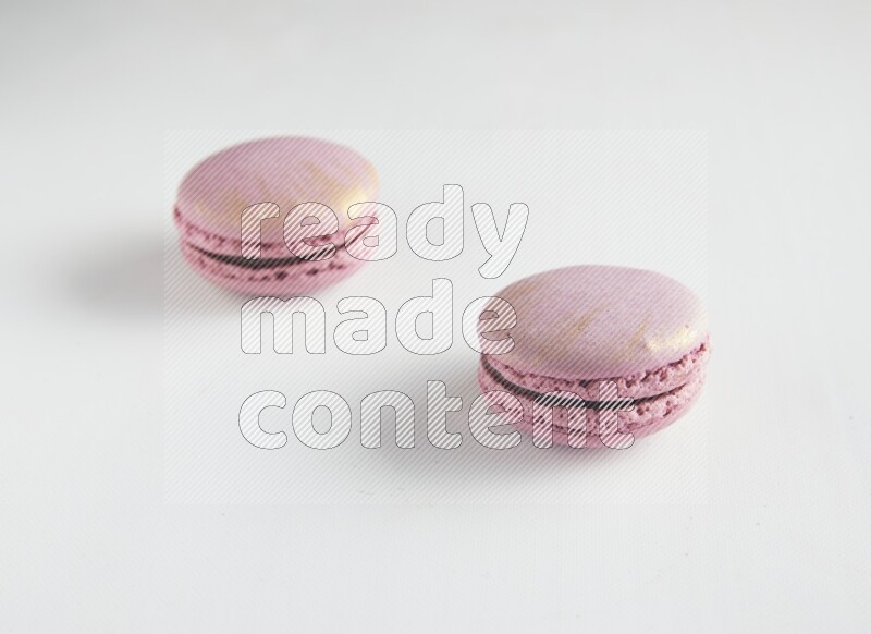 45º Shot of two Purple Strawberry macarons on white background