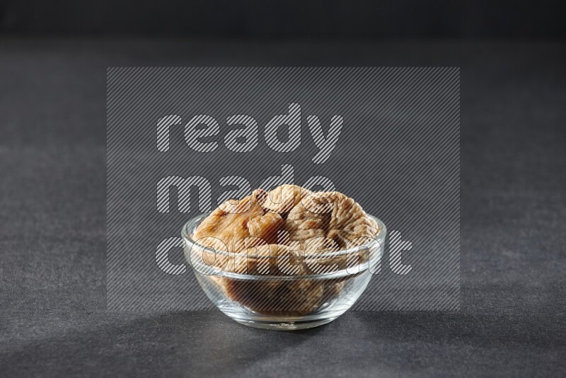 A glass bowl full of dried figs on a black background in different angles