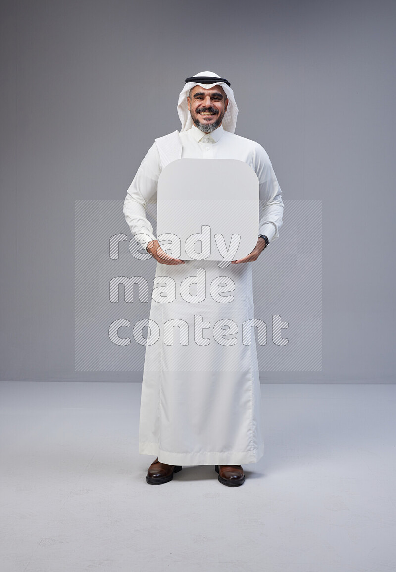 Saudi man Wearing Thob and white Shomag standing holding social media sign on Gray background