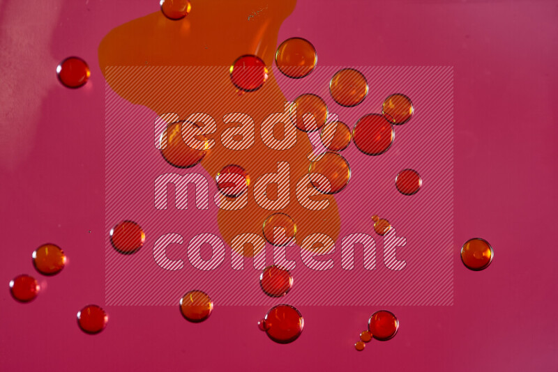 لقطات مقربة لقطرات ألوان مائية حمراء على سطح الزيت على خلفية وردية