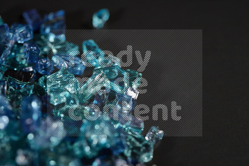 Transparent blue fragments of glass scattered on a black background