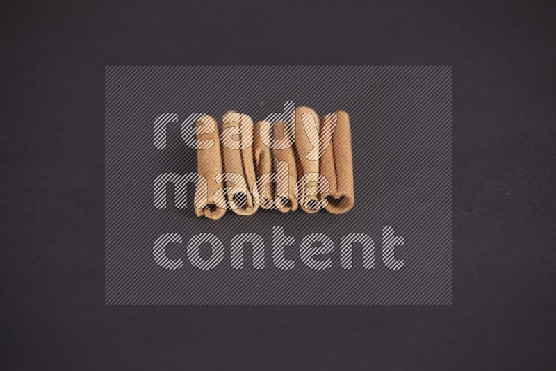 Cinnamon sticks stacked on black flooring