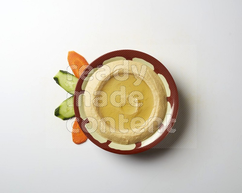 Hummus in a traditional plate garnished with olive oil on a white background