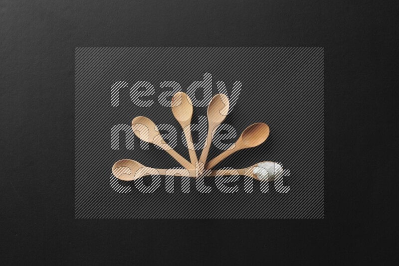 الفلفل الأبيض والقرنفل والهيل والملح والفلفل الأسود وريحان مجفف في معالق خشبية علي خلفية سوداء