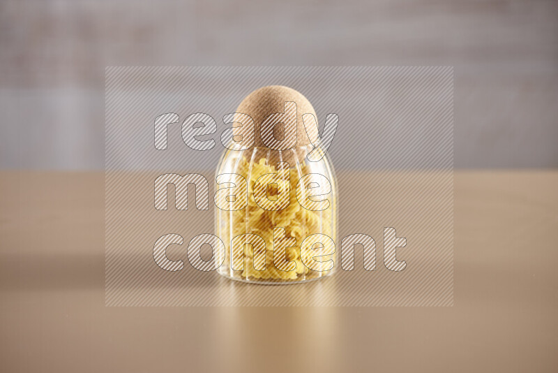 Raw pasta in glass jars on beige background