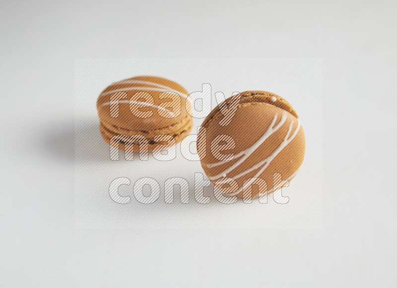 45º Shot of two Brown Irish Cream macarons on white background
