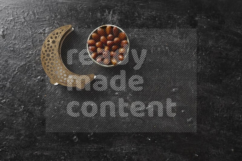 Dates in pottery bowl with a wooden lantern in a dark setup