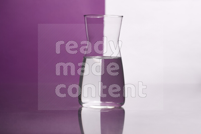 The image features a clear glassware filled with water, set against white and purple background