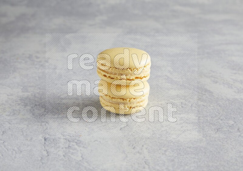 45º Shot of two Yellow Vanilla macarons  on white  marble background