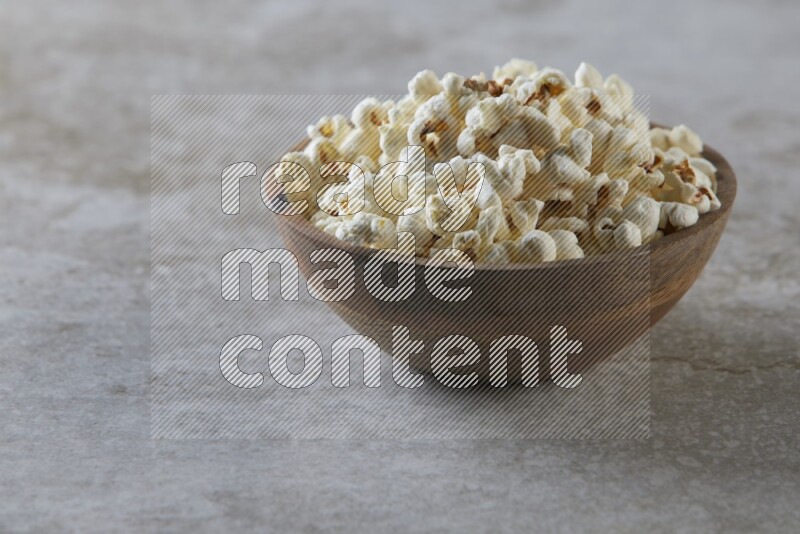 popcorn in wooden bowl on a grey textured countertop
