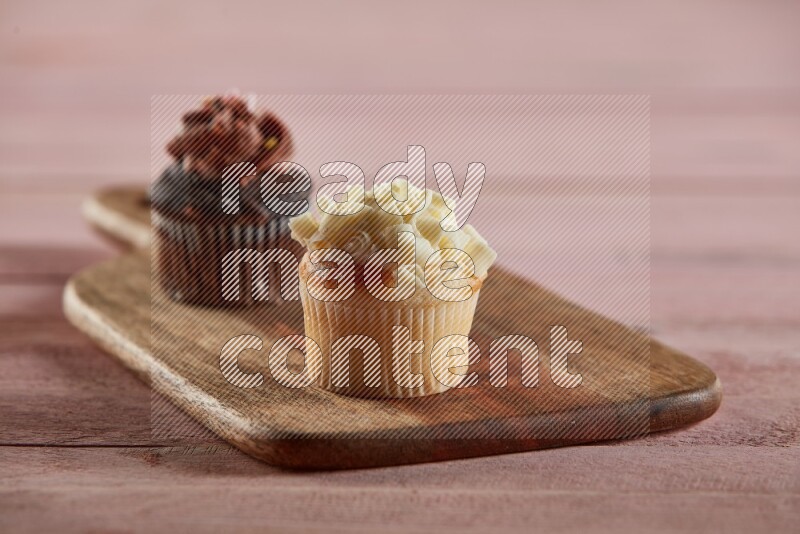 Vanilla mini cupcake topped with white chocolate curls on a wooden board