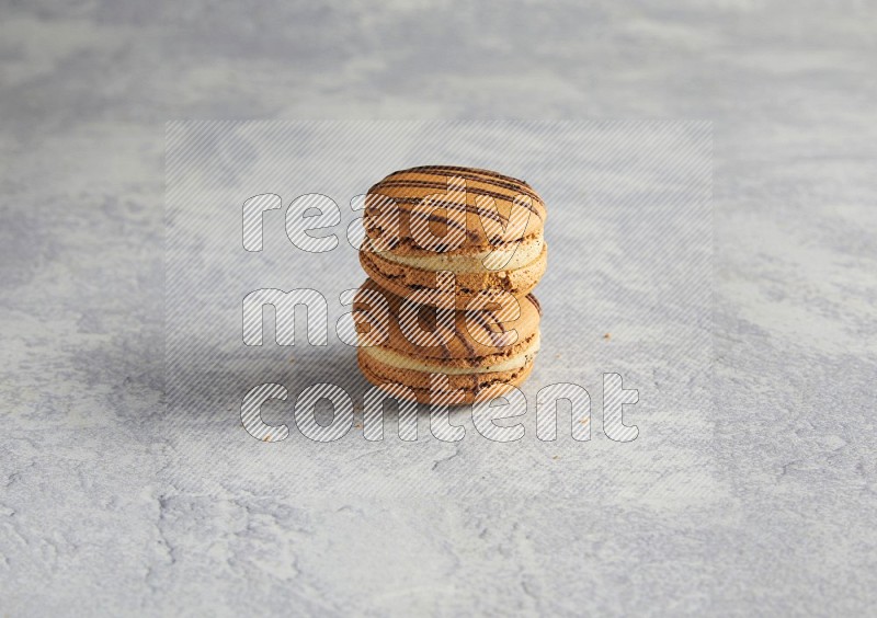 45º Shot of two light brown  Almond Cream macarons  on white  marble background