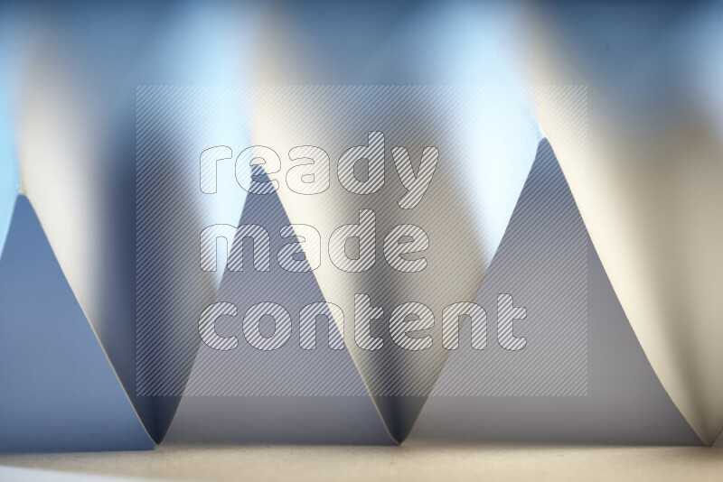 A close-up abstract image showing sharp geometric paper folds in white and blue gradients