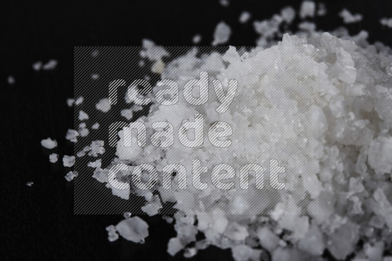 A bunch of coarse sea salt crystals on black background