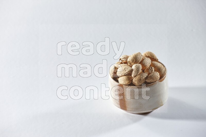 A beige ceramic bowl full of almonds on a white background in different angles