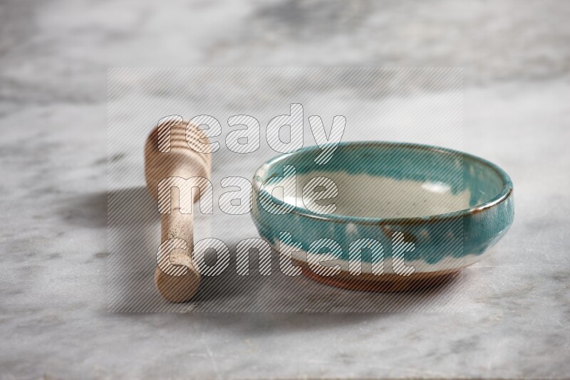 Multicolored pottery bowl with wooden honey dipper on the side on grey marble background