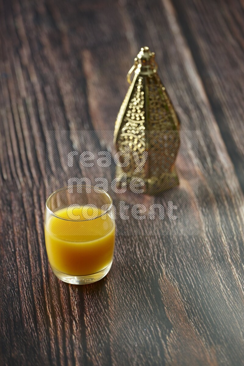 A golden lantern with different drinks, dates, nuts, prayer beads and quran on brown wooden background