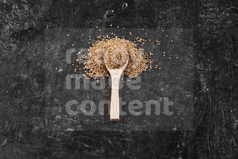 A wooden spoon full of mustard seeds on a textured black flooring in different angles