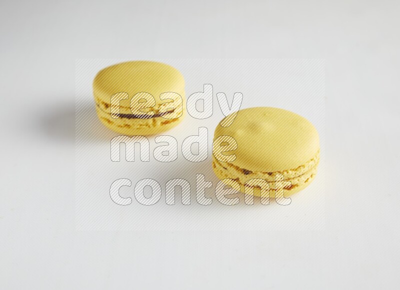 45º Shot of two Yellow Lemon macarons on white background