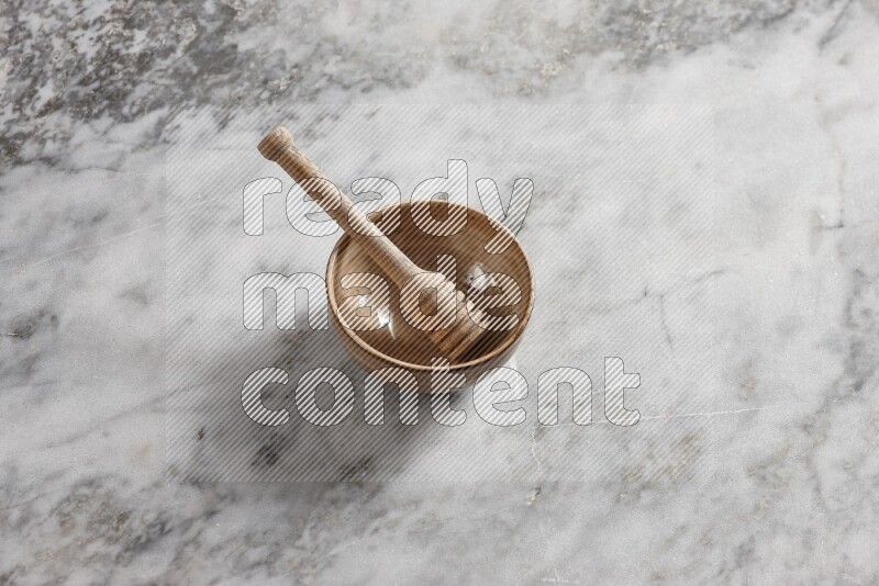 Beige pottery bowl with wooden honey dipper in it on grey marble background