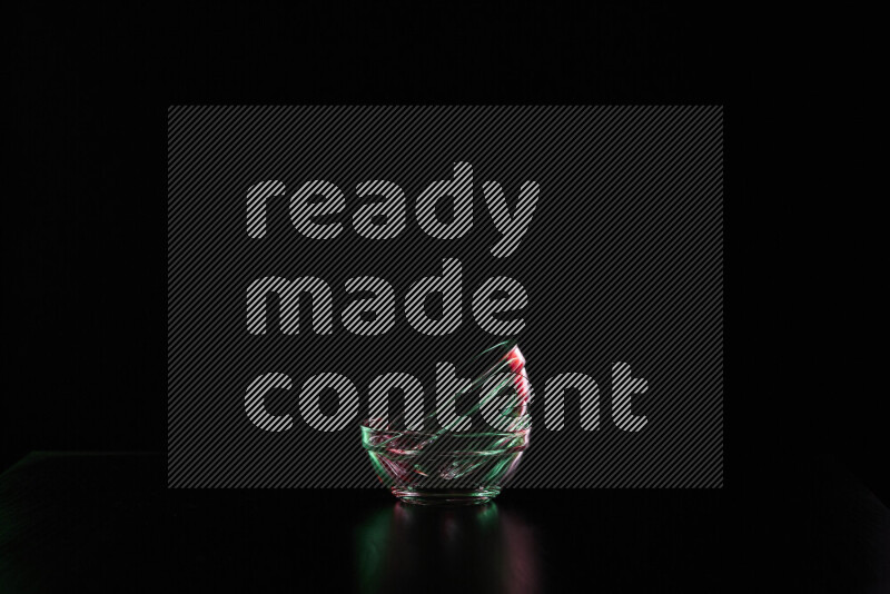 Glassware with rim light in red and green against black background