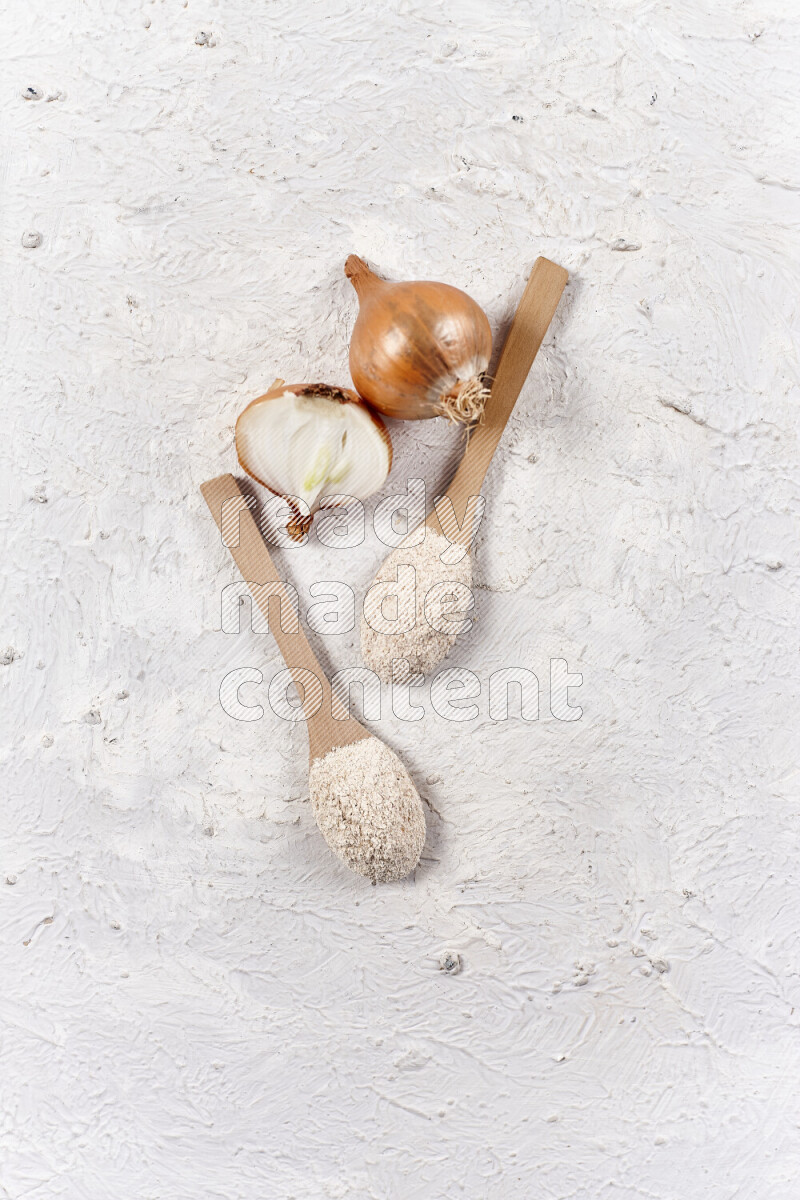 Two wooden spoons full of onion powder on white background