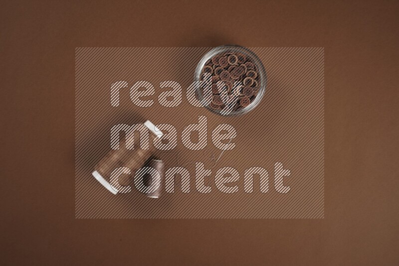 مجموعة من أدوات الخياطة والتفصيل بنية اللون على خلفية بنية