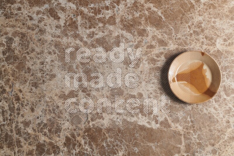 A multicolored pottery plate on beige marble background