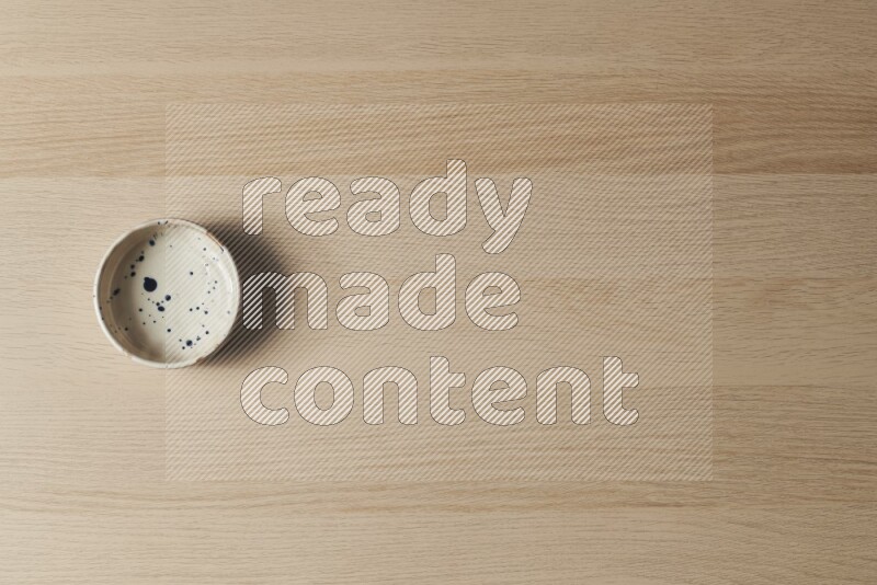 وعاء فخاري متعدد الألوان على خلفية خشبية فاتحة