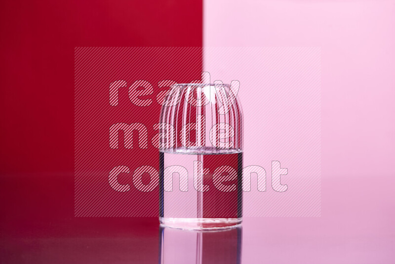 The image features a clear glassware filled with water, set against red and rose background