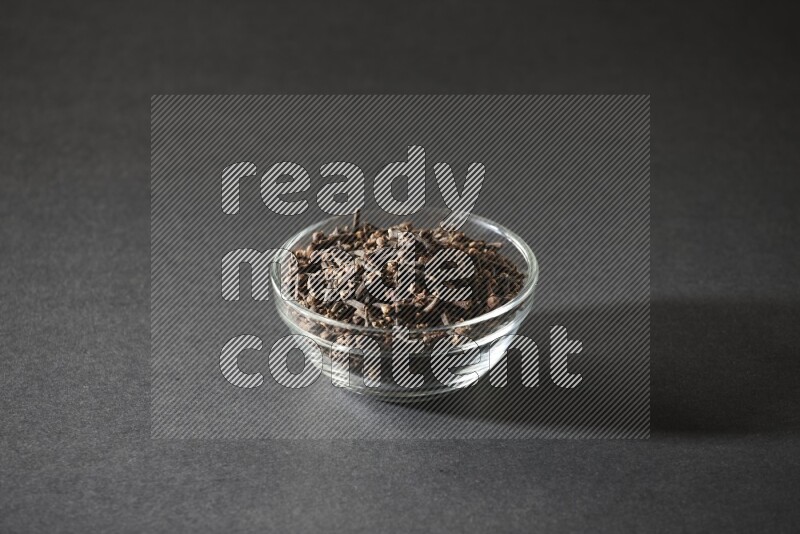 A glass bowl full of cloves on a black flooring