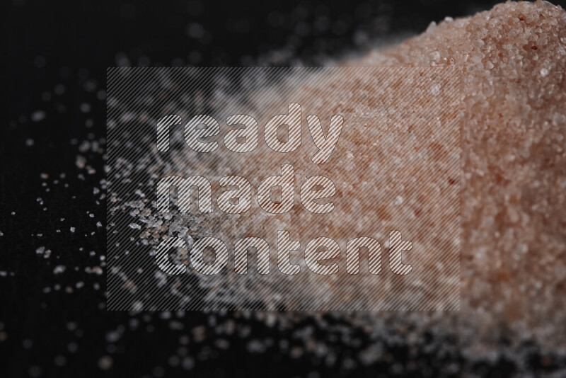 A bunch of fine himalayan pink salt on black background