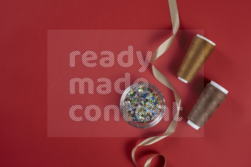 A brown and red collection of sewing and tailoring tools arranged on a red background