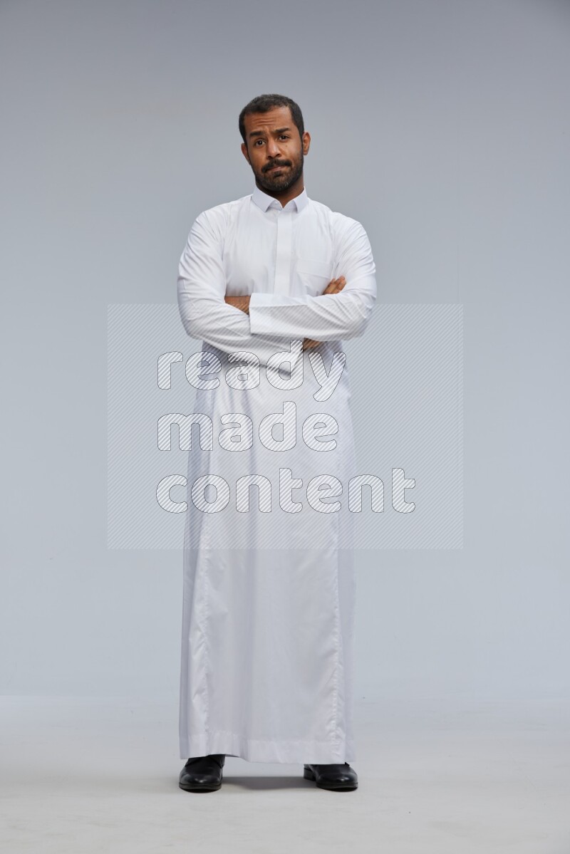 Saudi man wearing Thob standing with crossed arms on Gray background